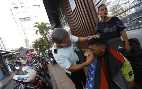 Darío corta el cabello en medio de la Bahía, al pie de una estación de Metrovía.