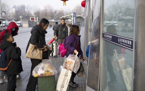 La gente empuja maletas fuera de la estación ferroviaria Oeste de Beijing en Beijing, China, 17 de febrero de 2024.