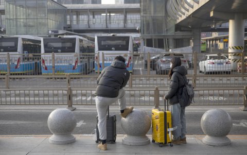 Personas con maletas esperan un taxi fuera de la estación de tren Oeste de Beijing en Beijing, China, 17 de febrero de 2024.