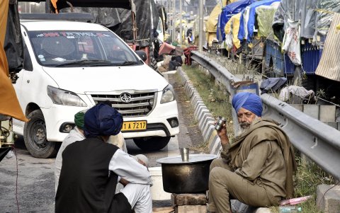 Los agricultores indios se sientan a lo largo de la carretera mientras esperan reanudar su marcha de protesta.