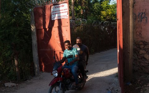 Dos hombres en motocicleta cruzan una de las barreras que vecinos de muchas calles han instalado para protegerse de la violencia de las pandillas, este domingo en Puerto Príncipe (Haití).