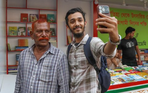 Shahjahan Bhuiyan (izq.) posa para un selfie con un asistente en el puesto de libros Kingbondonti durante la feria anual del libro en Dhaka, Bangladesh, 24 de febrero de 2024).