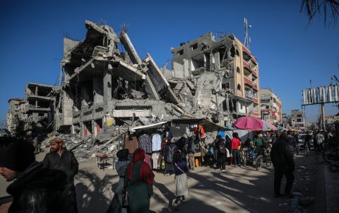 Palestinos caminan frente a edificios destruidos de Gaza, en el primer día del Ramadán musulmán.