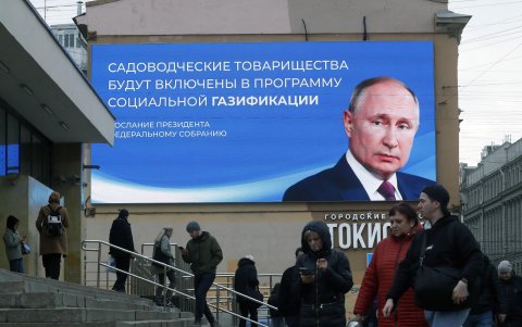 Ciudadanos pasan frente a una gigante pantalla digital con la imagen del presidente Vladimir Putin.