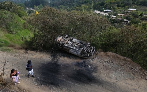 Pobladores caminan junto a un carro destruido en el que presuntamente se transportaban miembros del Estado Mayor Central (EMC), la mayor disidencia de las FARC, en la vereda La Bodega de Toribío.