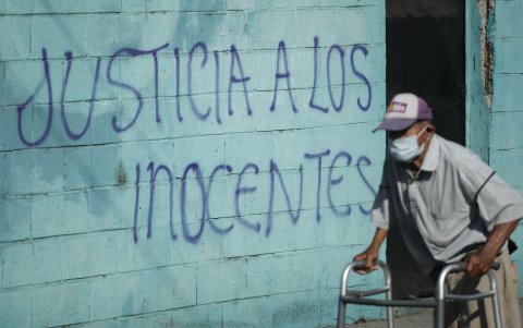 Un hombre camina frente a una pared pintada con la frase 'Justicia a los inocentes' en el Reparto La Campanera, uno de los barrios que registraba mayor presencia de pandillas, en Soyapango.