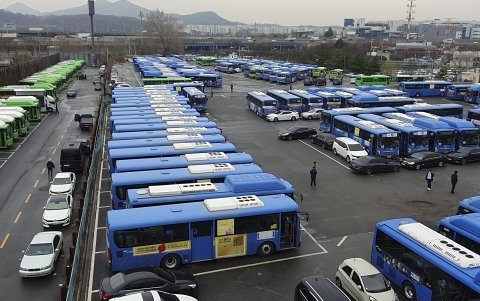 Los conductores caminan entre los autobuses parado en el estacionamiento público de autobuses Songpa en Seúl, Corea del Sur, 28 de marzo de 2024.