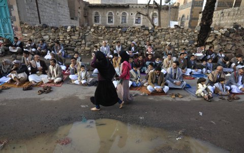 las niñas pobres pasan junto a las personas que asisten a las oraciones de Eid al-Fitr en Saná, Yemen, 10 de abril de 2024.