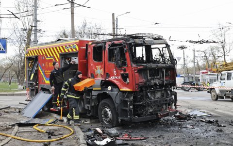 Dos bomberos ucranianos junto a un camión alcanzado por un ataque ruso en Járkov, Ucrania.