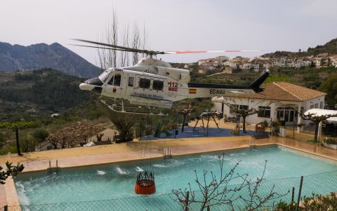 Un helicóptero carga agua en una piscina durante los trabajos de extinción del incendio forestal de Tárbena.