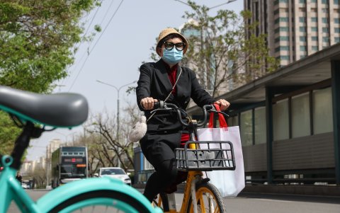 Una mujer anda en bicicleta en Beijing, China, 15 de abril de 2024. El Observatorio Meteorológico de Beijing emitió una alerta azul de tormenta de arena.