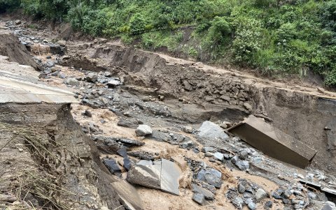 En la carretera, Parte de la estructura está hundida en el lodo, junto a piedras y postes caídos.