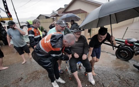 Un grupo de personas que ayuda a la evacuación de un adulto mayor en medio de la lluvia este miércoles, en Santa María, estado de Rio Grande do Sul.