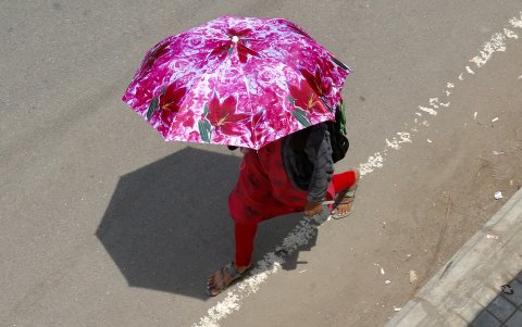 Una mujer se protege con un paraguas del calor en Bangalore, La India.
