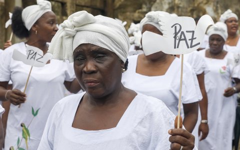 Una cantadora de Pogue sostiene un letrero que dice 'Paz' durante la conmemoración de los 22 años de la masacre de Bojayá