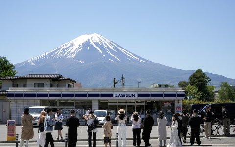 Turistas hacen fotografías de la tienda de la cadena Lawson con el Monte Fuji al fondo, en Fujikawaguchiko, al norte del Monte Fuji, Japón, el 10 de mayo de 2024.