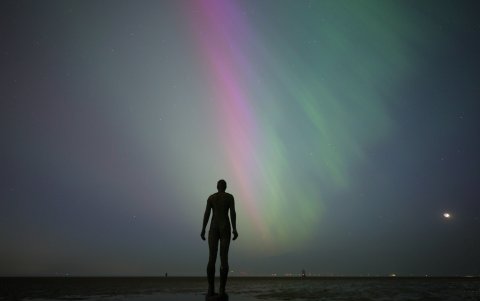 Fotografía de una Aurora Boreal frente a la escultura 