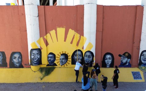 Activistas pintan un mural con rostros de migrantes deportados bajo el puente Internacional Paso del Norte, el 10 de mayo de 2024, en Ciudad Juárez (México).
