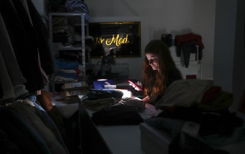 Una comerciante trabaja con ayuda de la linterna de su móvil en un comercio en el centro de Porto Alegre, afectado por la falta de electricidad provocada por las inundaciones y lluvias torrenciales.