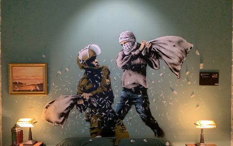 Un mural del artista Bansky que muestra a un policía fronterizo israelí en una pelea de almohadas con un palestino