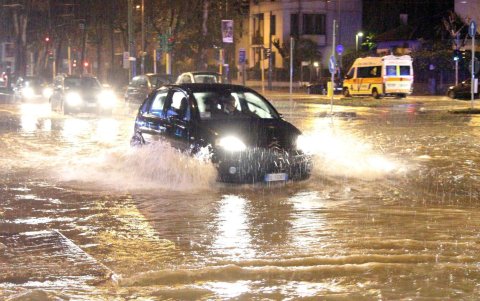 Un coche circula bajo la lluvia por una calle inundada tras desbordarse el río Seveso en Milán (Italia).