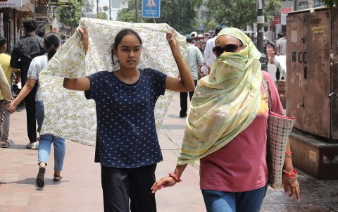 Dos mujeres caminan por una calle de Nueva Delhi, intentando cubrirse del sol inclemente que afecta en estos días en la capital de La India.