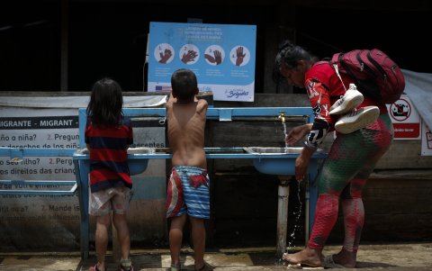 Una mujer y dos niños migrantes tras cruzar la selva del Darién en Lajas Blancas (Panamá