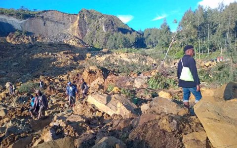 Una vasta área de rocas y tierra arrancada de una colina, así como a vecinos recogiendo sus enseres