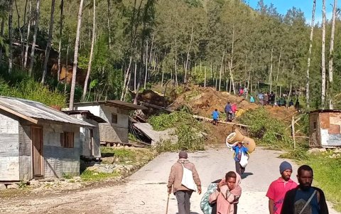 La gente camina con sus pertenencias en la zona donde un deslizamiento de tierra azotó la aldea de Kaokalam, provincia de Enga, Papúa Nueva Guinea, el 24 de mayo de 2024.