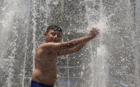 Un niño se baña en una fuente pública, debido a las altas temperaturas registradas en la Ciudad de México