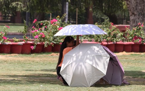 Unas personas se protegen con sombrillas una tarde de sol.