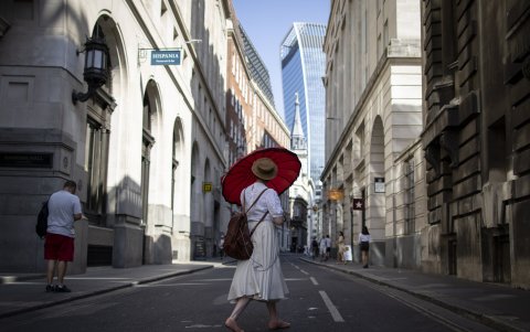 Una mujer usa un paraguas para protegerse del sol en el distrito financiero de la ciudad de Londres, Reino Unido.