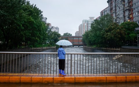Una mujer observa la crecida de un río en Pekín, China.