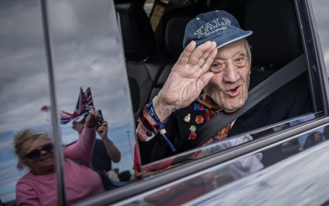 El veterano británico de la Segunda Guerra Mundial, Joe Mines, saluda desde un automóvil después de una ceremonia de bienvenida.