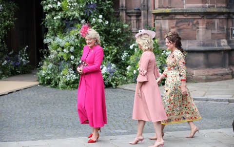 La madre del novio y su madrina de bodas, la duquesa Natalia Grosvenor, viuda de Gerald Grosvenor, apostó por un traje fucsia manga larga, que complementó con un broche y zapatos slingback rojos. El tocado de plumas y el clutch con estampado de corazones cierran el look. Al casarse su hijo, asume el título de Su Alteza Natalia, duquesa de Westminster o Su Alteza la duquesa viuda.