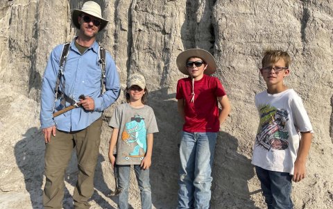 El paleontólogo Tyler Lyson mientras posa con Liam Fisher, Jessin Fisher y Kaiden Madsen, quienes descubrieron el fósil de un joven dinosaurio Tiranousario Rex (T-Rex).