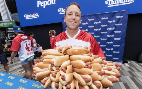 Joey Chestnut sostiene un plato de 76 hot dogs.
