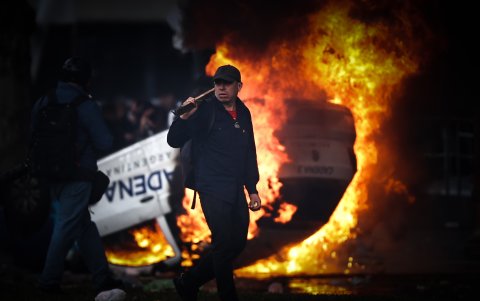 Un hombre camina frente a una carro en llamas durante una protesta a las afueras del Senado argentino.