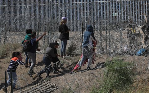 Un grupo de migrantes merodean un sector del cerco fronterizo.