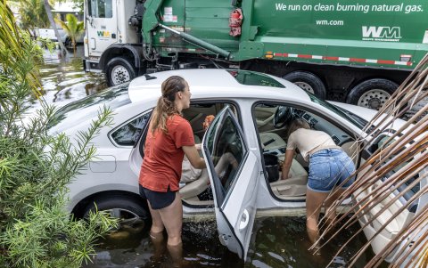 Dos personas junto a un automóvil en un vecindario inundado en Hallandale Beach, Florida, EE. UU., 13 de junio de 2024.