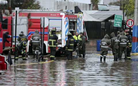 Personal de Carabineros y bomberos trabajan en calles inundadas por la lluvia este jueves, en Santiago (Chile).