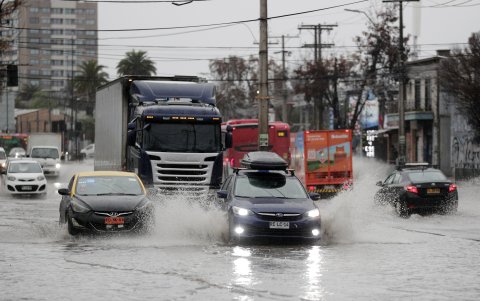 Vehículos transitan por calles inundadas causadas por la lluvia este jueves, en Santiago (Chile).