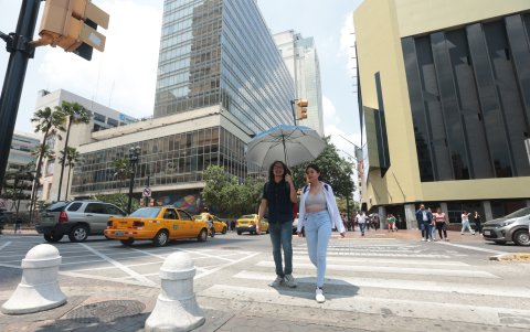 Un par de personas atraviesa una calle de Guayaquil en un día de mucho sol.