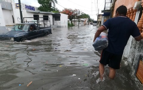 Un hombre y vehículo circulan por una calle inundada debido a las fuertes lluvias, este martes en Cancún, estado de Quintana Roo (México).