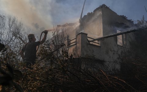 Residentes y voluntarios intentan apagar un incendio en una casa que arde después de que se produjera un incendio en Varis - Koropiou, al este de Ática, Grecia, el 19 de junio de 2024.
