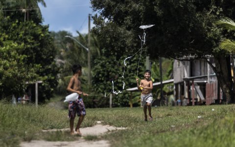 Un indígena caminando en una zona deforestada donde se encuentra una estructura de metal pintada de rojo que sirve para mantener la presión y controlar el flujo de gas.