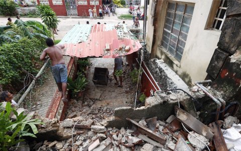 Un hombre limpia los escombros de una vivienda afectada por las fuertes lluvias, este domingo en La Habana (Cuba).