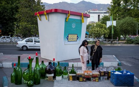 Dos mujeres observan un puesto callejero colocado ante una maqueta gigante de una urna para urgir a los iraníes a votar en las elecciones presidenciales del 28 de junio.