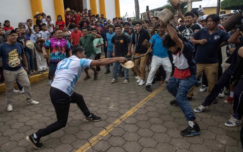 Dos hombres se dan latigazos mientras realizan el baile de los Chinegros este lunes durante las festividades en honor a San Juan Bautista en la ciudad de San Juan de Oriente (Nicaragua).