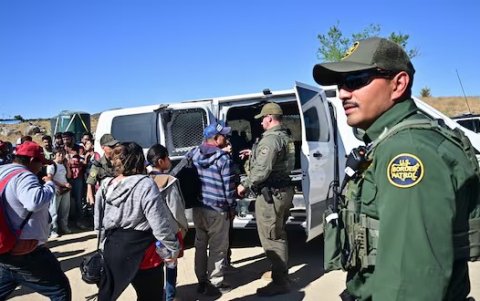 Agentes de Aduanas y Patrulla Fronteriza cargan a migrantes en un vehículo después de que grupos de migrantes ingresaron a los EE.UU.